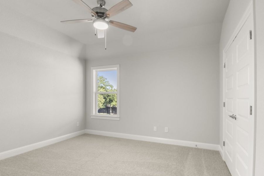 Image of a bedroom with tan carpeting and light grey walls with a window and a ceiling fan Image of a bedroom with tan carpeting and light grey walls with a window and a ceiling fan