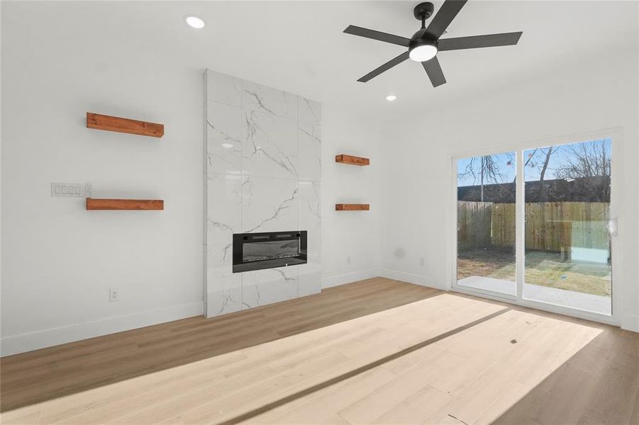 Unfurnished living room featuring light wood finished floors, ceiling fan, a fireplace, and recessed lighting
