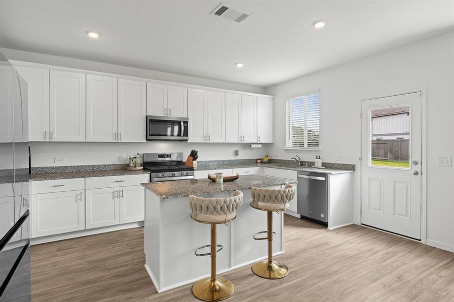 An additional view of the Gourmet Kitchen with picture window, an abundance of storage and counter space, and oversized kitchen island w/ breakfast bar.