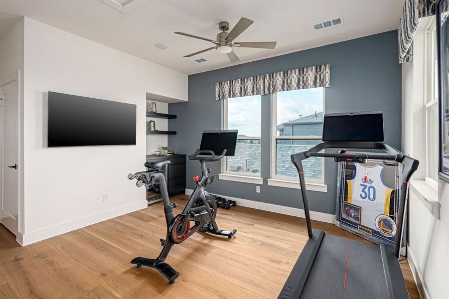 Workout area with light wood-type flooring and a ceiling fan