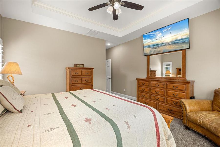 Bedroom featuring a tray ceiling, crown molding, carpet flooring, and a ceiling fan Bedroom featuring a tray ceiling, crown molding, carpet flooring, and a ceiling fan