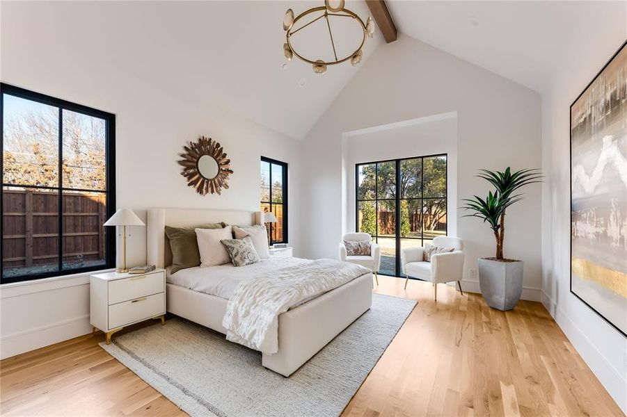 Bedroom featuring beamed ceiling, access to exterior, high vaulted ceiling, and light wood-type flooring