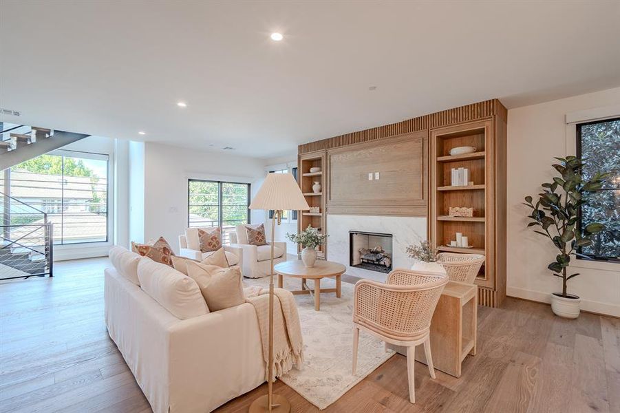 Living area with stairway, light wood-type flooring, a high end fireplace, recessed lighting, and built in features Living area with stairway, light wood-type flooring, a high end fireplace, recessed lighting, and built in features
