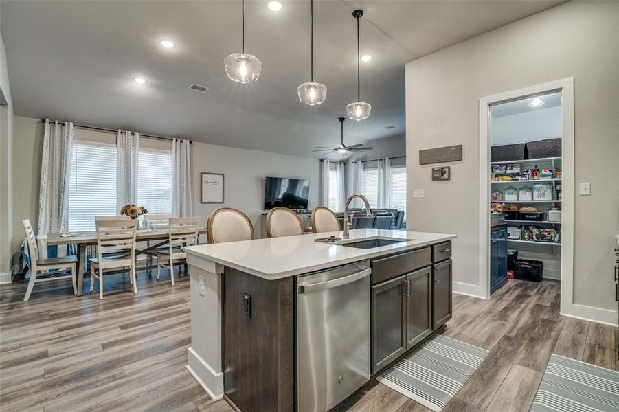 Kitchen with dishwasher, a kitchen island with sink, sink, hanging light fixtures, and ceiling fan