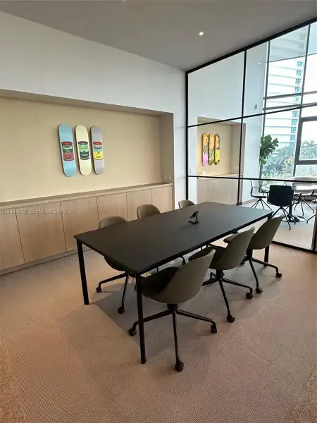 Floor-to-ceiling metal-framed glass wall, recessed built-in wood-finish cabinetry, and neutral carpeting Floor-to-ceiling metal-framed glass wall, recessed built-in wood-finish cabinetry, and neutral carpeting