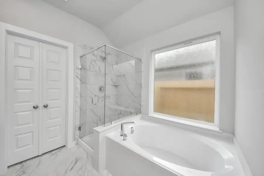 Indulge in a spa-like retreat within the confines of this primary bathroom. Delight in a spacious walk-in shower enveloped in stylish tile surround and unwind in a separate garden tub adorned with custom detailing. Sample photo of completed home with similar floor plan. Actual colors and selections may vary. Indulge in a spa-like retreat within the confines of this primary bathroom. Delight in a spacious walk-in shower enveloped in stylish tile surround and unwind in a separate garden tub adorned with custom detailing. Sample photo of completed home with similar floor plan. Actual colors and selections may vary.