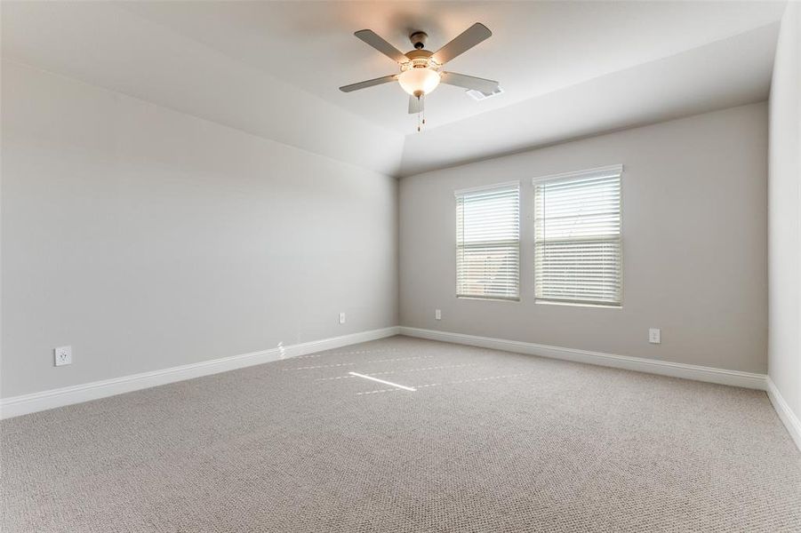 Carpeted spare room featuring a ceiling fan and vaulted ceiling