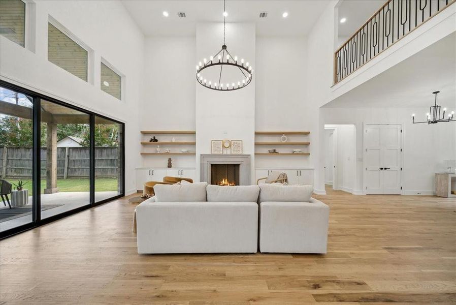 Living room featuring a high ceiling, hardwood flooring, and a notable chandelier