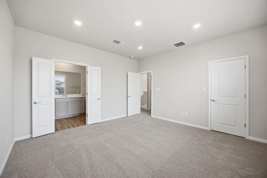 Unfurnished bedroom featuring light colored carpet, connected bathroom, and recessed lighting