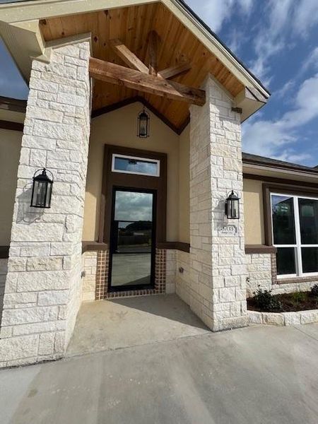 Doorway to property featuring stone siding and stucco siding