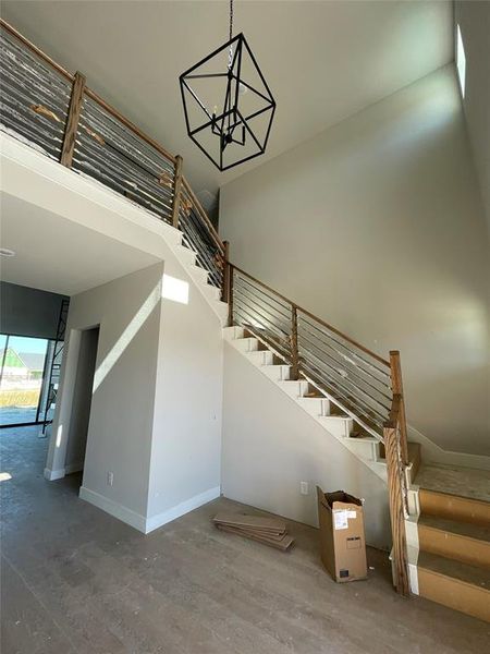 Stairway with wood finished floors and a chandelier