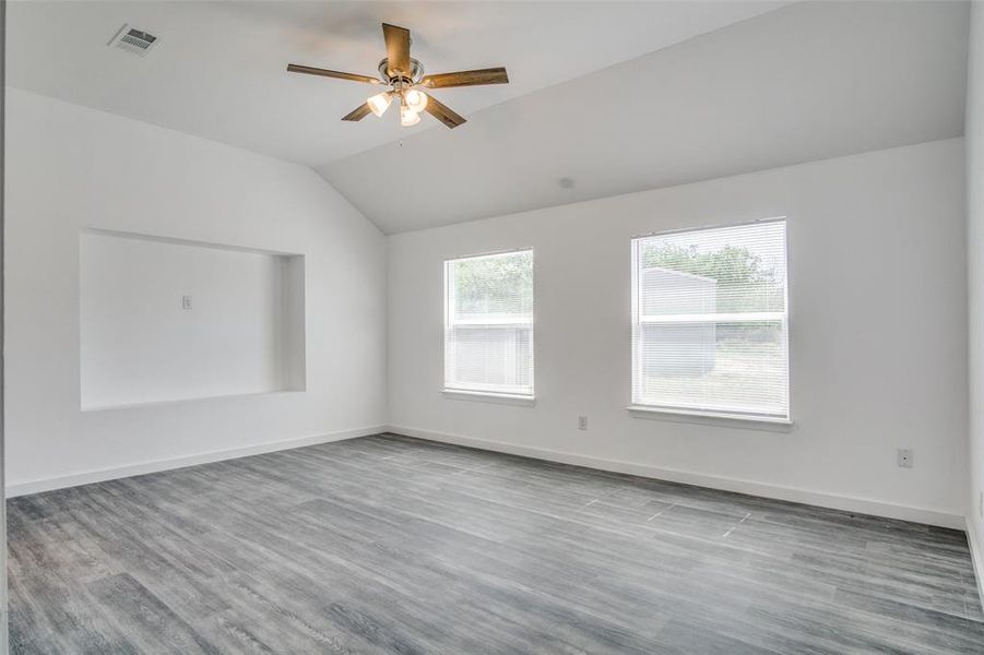 Empty room with wood-type flooring, vaulted ceiling, and ceiling fan Empty room with wood-type flooring, vaulted ceiling, and ceiling fan