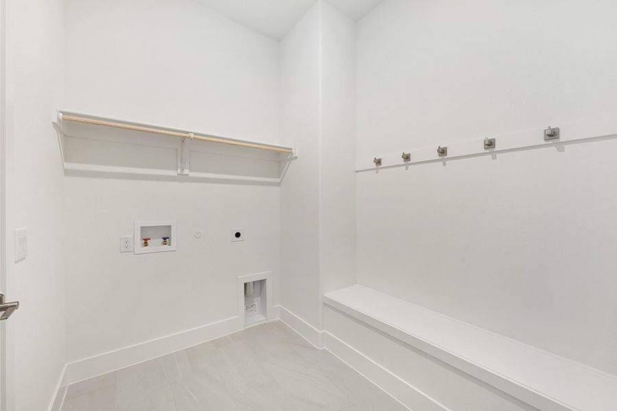 Mudroom and laundry area with built-in bench, coat hooks, shelf, and washer hookups on white walls Mudroom and laundry area with built-in bench, coat hooks, shelf, and washer hookups on white walls