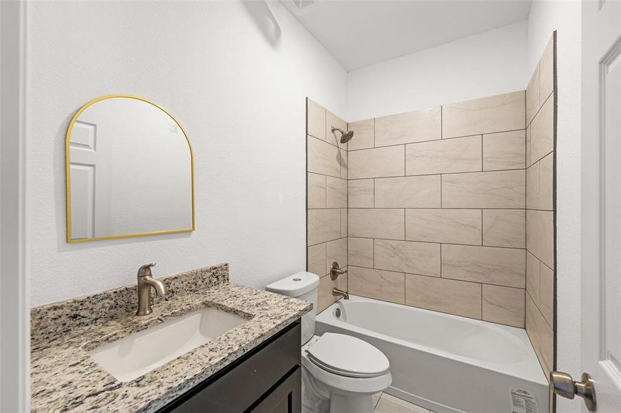 Full bathroom with vanity, tiled shower / bath combo, and toilet