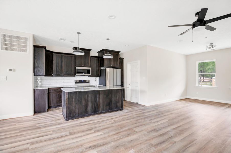 Kitchen view with subway tile back splash, granite counters and stainless appliances. Door to the right is our utility room which is very convenient!