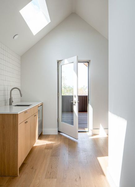 Kitchen with modern cabinets, light wood-style flooring, lofted ceiling, a skylight, and light brown cabinetry