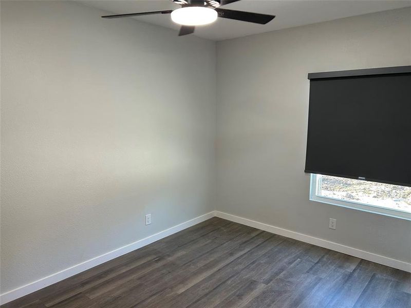 Spare room featuring dark wood-style flooring and a ceiling fan Spare room featuring dark wood-style flooring and a ceiling fan