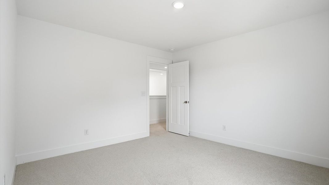 Bright and serene bedroom with comfortable carpeted flooring and large windows for vibrant light
