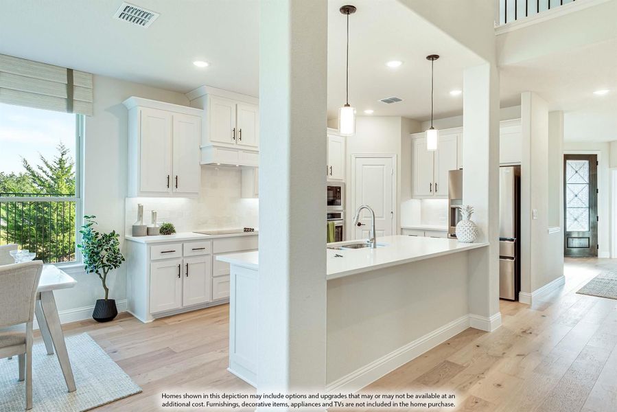 Open kitchen with white cabinets, large island, pendant lights, and light hardwood floors