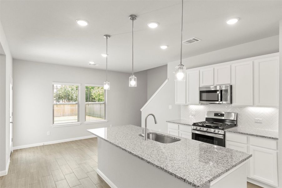Kitchen featuring stainless steel appliances, a sink, decorative backsplash, baseboards, and recessed lighting