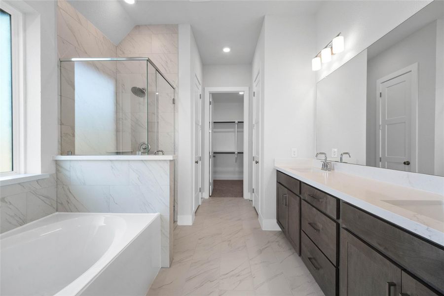 This stunningly updated primary bathroom is truly move-in ready! It features stained cabinetry with light countertops, dual vanities, a large mirror, a generous walk-in closet with built-in shelving, soaring ceilings, custom paint, and sleek modern finishes throughout.