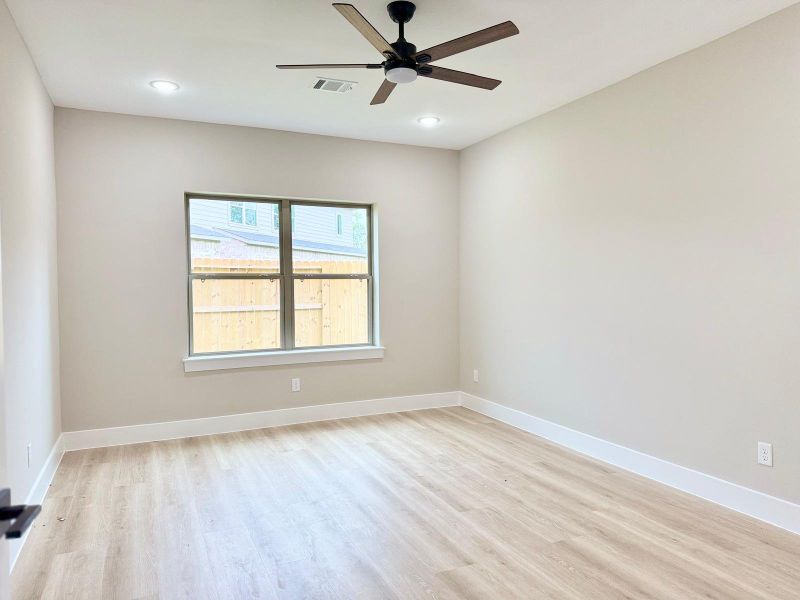 Spacious and serene primary bedroom featuring ample natural light and modern ceiling fan for ultimate comfort.