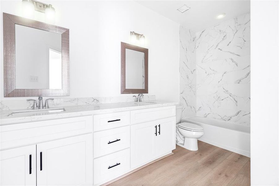 The spacious secondary bathroom rivals the master, featuring a large countertop with dual sinks, two mirrors, and plenty of cabinet space. (Photo may be enhanced)