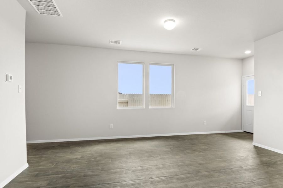 Image of a one story home living room with brown flooring and grey walls and two windows