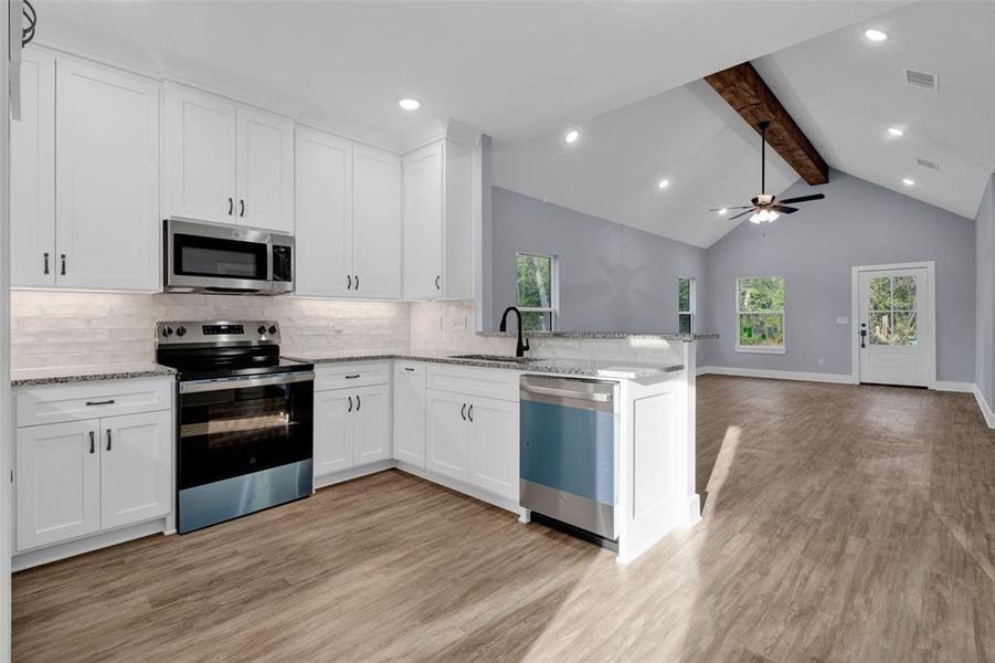 Kitchen with stainless steel appliances, open floor plan, recessed lighting, light stone counters, and backsplash