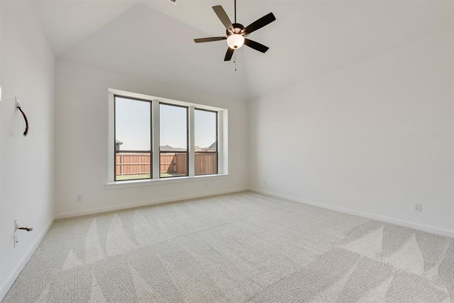 Carpeted empty room featuring ceiling fan and high vaulted ceiling Carpeted empty room featuring ceiling fan and high vaulted ceiling