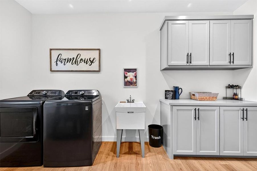 Washroom featuring light wood-type flooring, washer and dryer, and cabinet space Washroom featuring light wood-type flooring, washer and dryer, and cabinet space