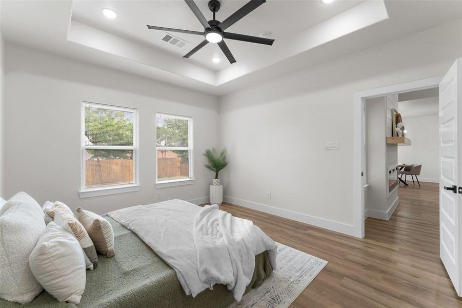 Bedroom with a tray ceiling, wood finished floors, recessed lighting, baseboards, and ceiling fan Bedroom with a tray ceiling, wood finished floors, recessed lighting, baseboards, and ceiling fan
