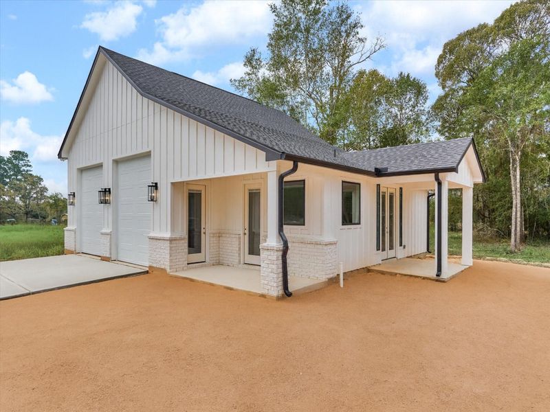 Modern Casita retreat with 438 sqft featuring clean architectural lines, fresh board-and-batten siding, dual garage bays, and a welcoming covered entry—perfectly paired with serene natural surroundings for a luxe, private guest experience.