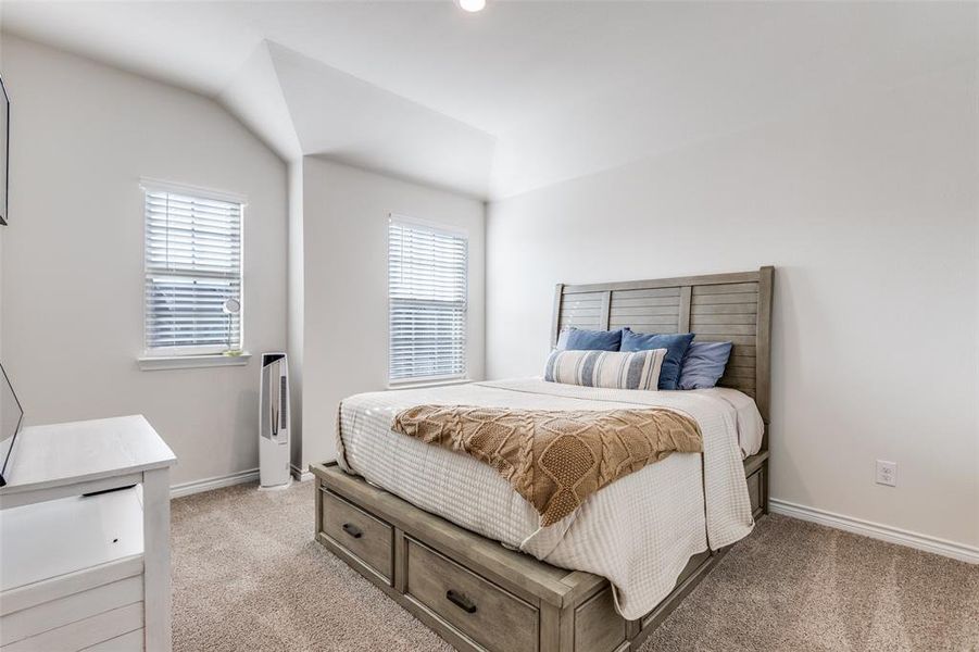 Bedroom featuring multiple windows, light colored carpet, and vaulted ceiling Bedroom featuring multiple windows, light colored carpet, and vaulted ceiling