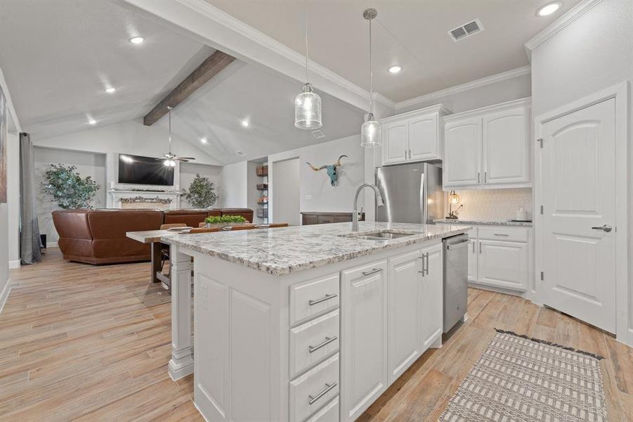 Kitchen with white cabinetry, open floor plan, ceiling fan, light stone countertops, and hanging light fixtures