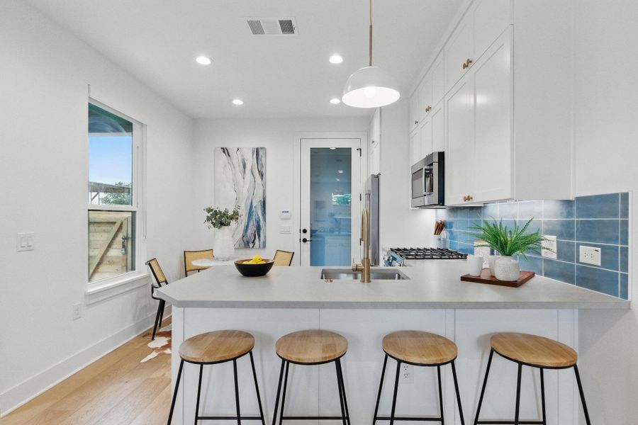 Kitchen featuring a peninsula, white cabinets, a kitchen breakfast bar, light countertops, and recessed lighting Kitchen featuring a peninsula, white cabinets, a kitchen breakfast bar, light countertops, and recessed lighting