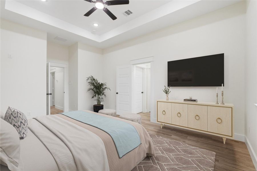 The well-designed primary bedroom features an 11-foot tray ceiling with a ceiling fan and recessed lighting.