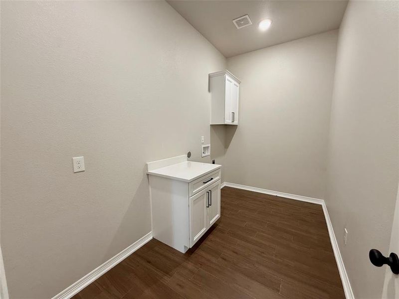 Washroom with dark wood finished floors, cabinet space, and hookup for a washing machine Washroom with dark wood finished floors, cabinet space, and hookup for a washing machine