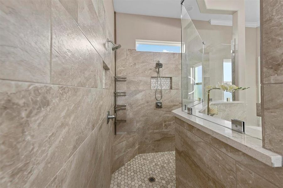 Bathroom with a tile shower and ornamental molding