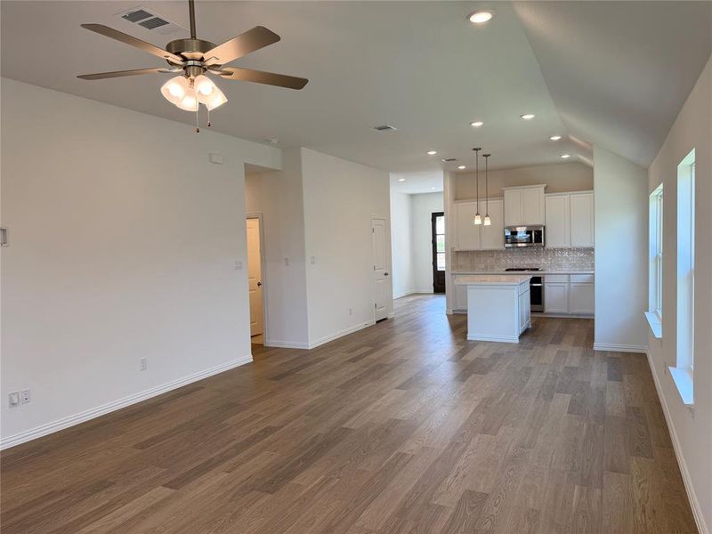 Expansive open-concept space featuring wood-finish flooring, recessed lighting, and a modern ceiling fan