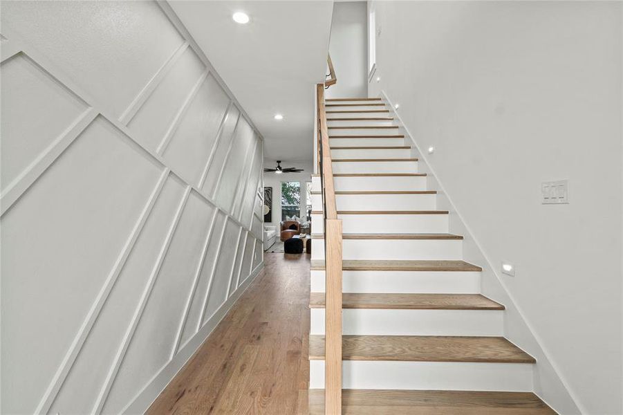 Stairs with wood finished floors and recessed lighting