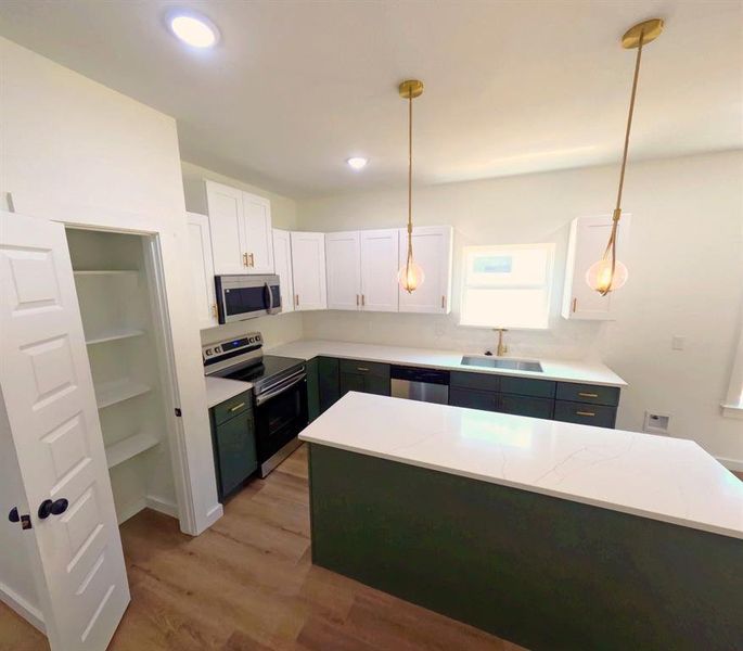 Kitchen featuring white cabinetry, stainless steel appliances, pendant lighting, light wood finished floors, and recessed lighting Kitchen featuring white cabinetry, stainless steel appliances, pendant lighting, light wood finished floors, and recessed lighting