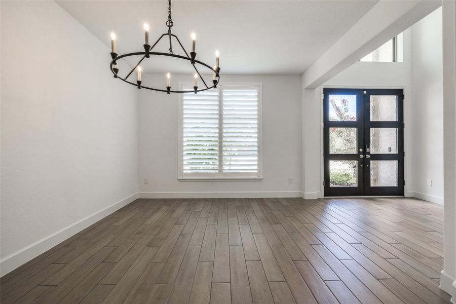 Large Dining Room to the front of the home with gorgeous black Chandelier, white plantation shuettrs