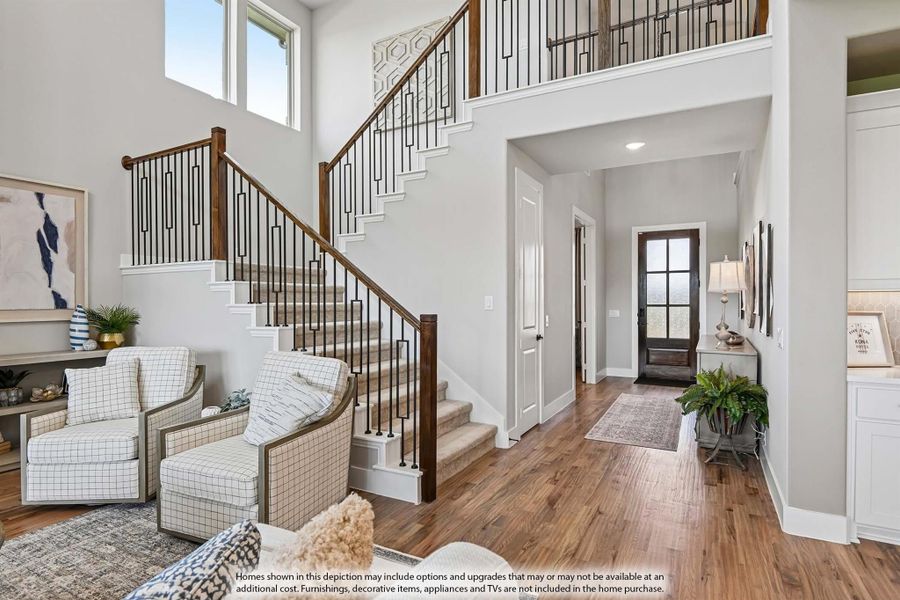 Two-story foyer with wood and iron staircase, hardwood floors, and front door entry hall Two-story foyer with wood and iron staircase, hardwood floors, and front door entry hall