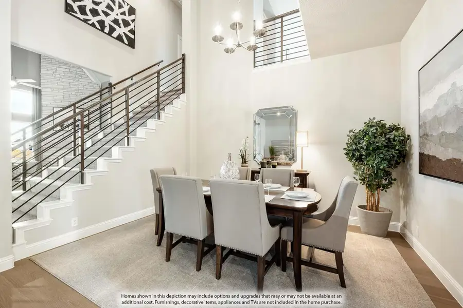 Dining room with two-story ceiling, wood staircase, chandelier, and six-seat dining table on area rug