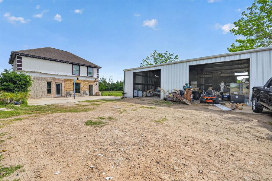 Exterior view showing Property 2 semi-finished residence and Property 3 metal outbuilding with open yard space.