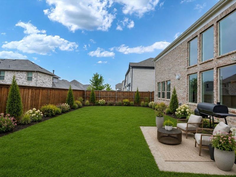 Expansive grassy lawn bordered by mature landscaping and a stained wood privacy fence Expansive grassy lawn bordered by mature landscaping and a stained wood privacy fence