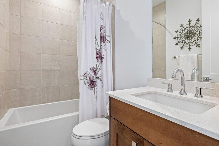 Bathroom featuring a spacious soaking tub, neutral subway tile surround, integrated sink with chrome faucet, and a wood-finish vanity