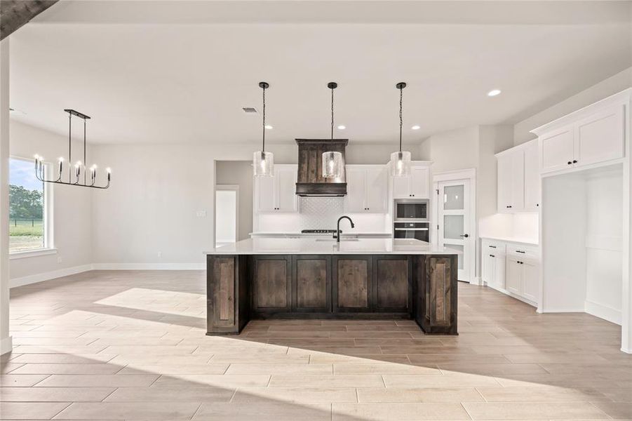 Kitchen with wood tiled floors, stainless steel microwave, light countertops, white cabinets, and baseboards Kitchen with wood tiled floors, stainless steel microwave, light countertops, white cabinets, and baseboards