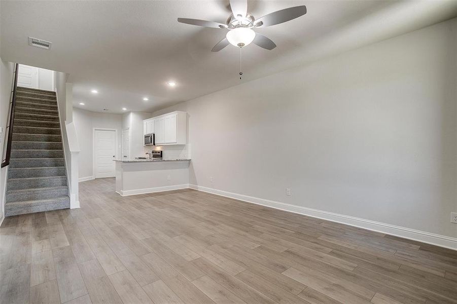 Unfurnished living room featuring stairway, light wood-style floors, recessed lighting, and ceiling fan Unfurnished living room featuring stairway, light wood-style floors, recessed lighting, and ceiling fan